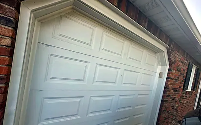 White raised-panel garage door on a brick home